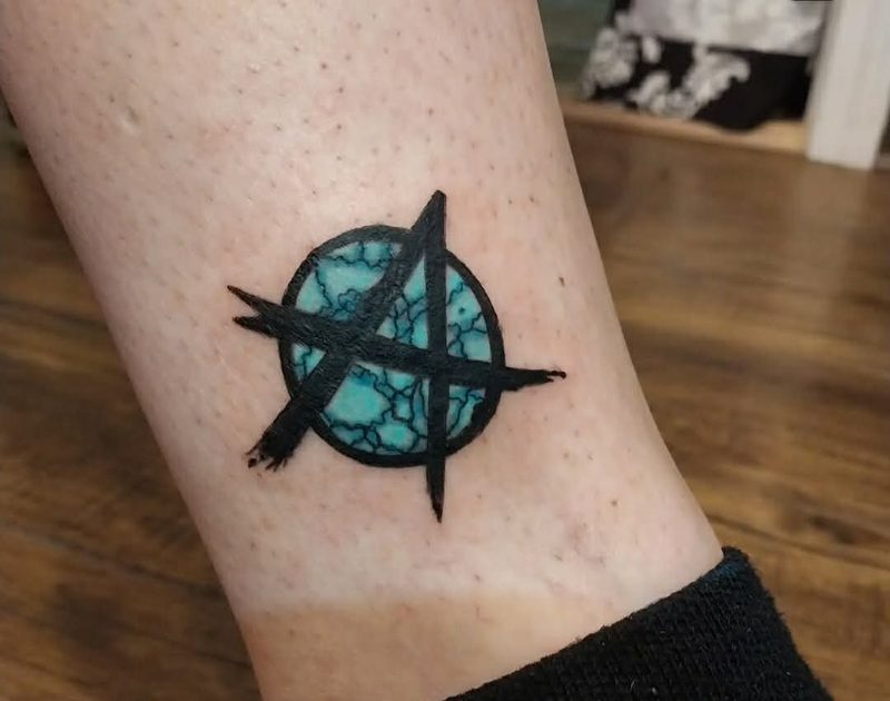 The same spot after cover-up: bold solid black linework over a turquoise stone texture