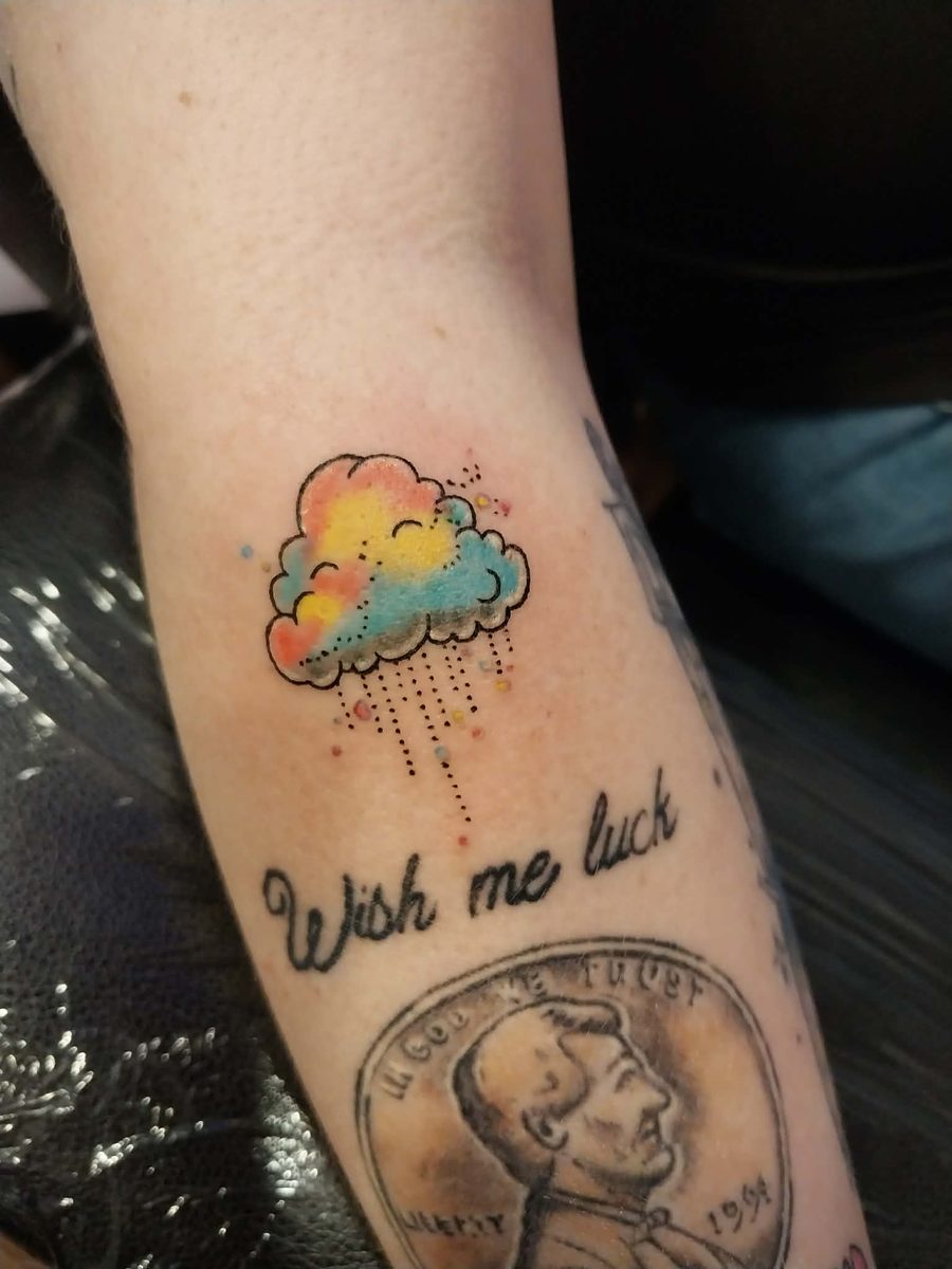 Watercolour-style rain cloud in coral, yellow and blue with dotted rain, above script lettering