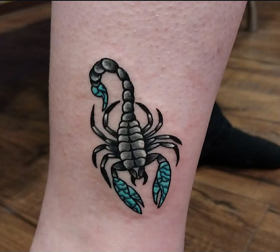 Traditional-style scorpion with teal claws and stinger, on a lower leg
