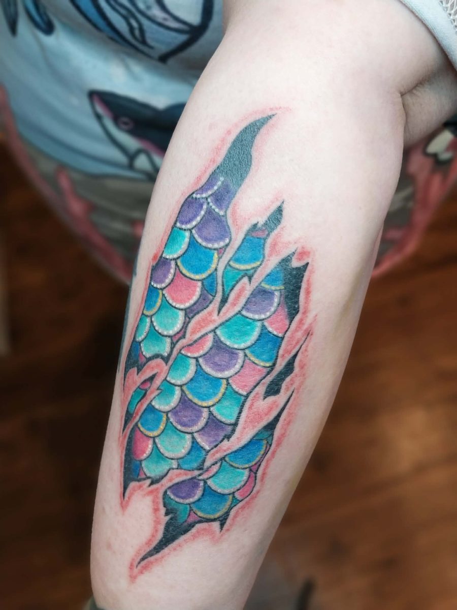 Torn-skin effect piece revealing teal, purple and pink scales underneath