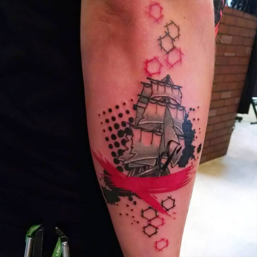 Trash polka style sailing ship in grey wash with a red brushstroke and geometric accents, on a forearm