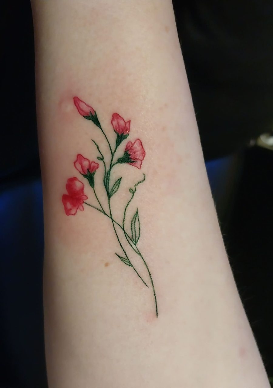 Fine line sweet pea flowers in pink with green stems, on a forearm